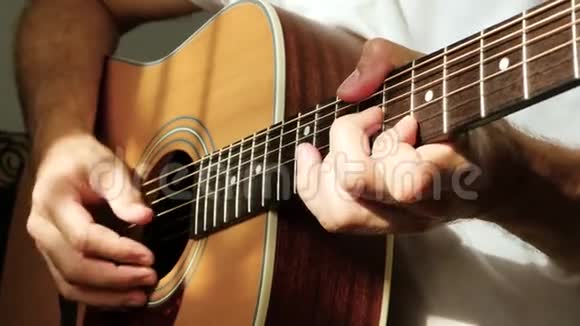 这位音乐家用他的手指在黄色的吉他上演奏一束光线落在手指和脖子上视频的预览图