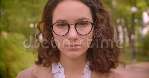 戴眼镜的白种人年轻的长毛卷曲女学生的特写肖像笑着兴高采烈地看着镜头视频的预览图