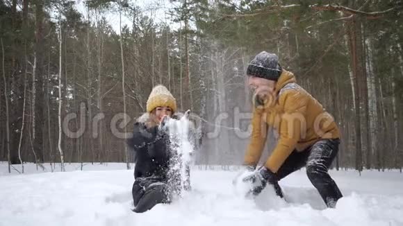 一对夫妇女孩和男人正在冬天的森林里缓慢地互相扔雪视频的预览图