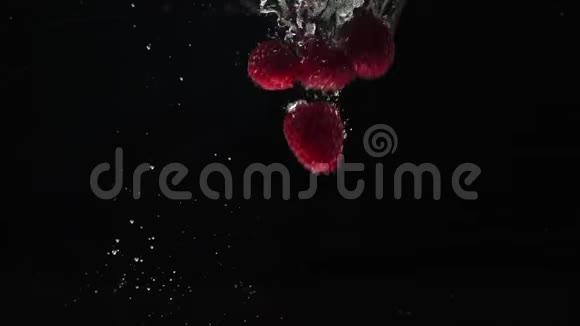 新鲜健康食品红色覆盆子在黑色背景下落入水中新鲜水果溅在水族馆里有机浆果视频的预览图