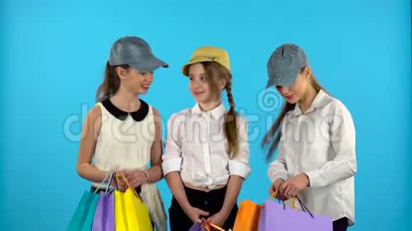 三个女购物者穿着购物袋看着很高兴蓝色背景视频的预览图