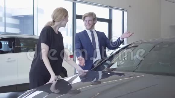 男人和女人穿着正式服装刚刚在现代车展上买了车女士既兴奋又快乐她拥抱汽车视频的预览图