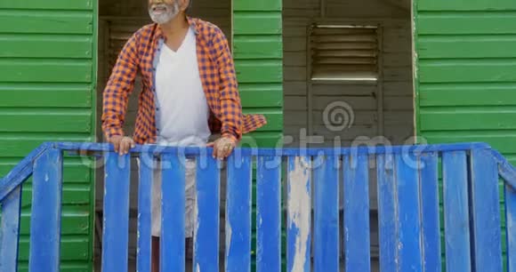 在阳光明媚的4k天气里站在海滩小屋的快乐活跃的非裔美国老人的正面景色视频的预览图
