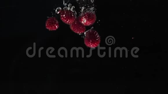 新鲜健康食品红色覆盆子在黑色背景下落入水中新鲜水果溅在水族馆里有机浆果视频的预览图