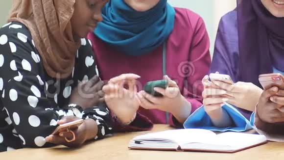 穆斯林多民族女孩看着手中的智能手机近距离观看视频的预览图