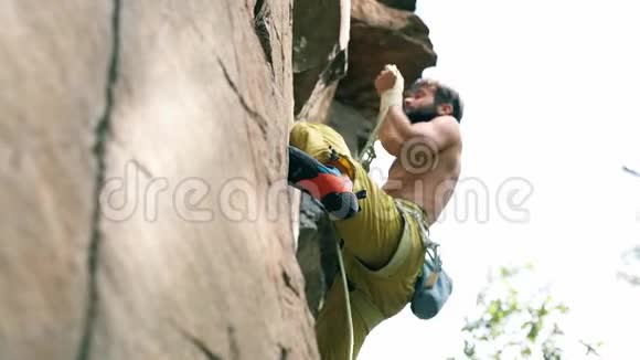 慢速运动爬坡瞬间和细节运动男子攀岩者裸躯干爬上悬崖视频的预览图