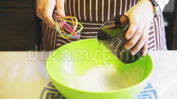 在家庭厨房的绿色碗里一只雌性的手在面粉中加入水烹饪煎饼视频的预览图