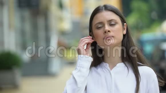 美丽的女人戴着无线耳机在城市街头享受音乐视频的预览图