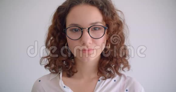 年轻可爱的长头发的卷曲的白种人女性的特写镜头她高兴地戴着眼镜看着镜头视频的预览图