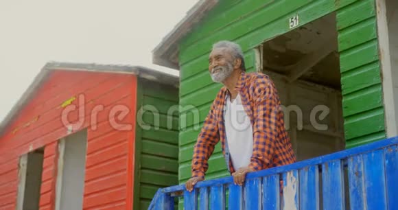在阳光明媚的4k天气里站在海滩小屋的快乐活跃的非裔美国人老人的低角度视角视频的预览图