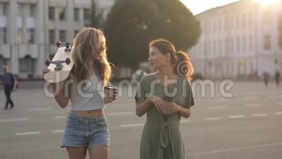 两个女孩十几岁的朋友在外面笑着喝咖啡慢动作视频的预览图