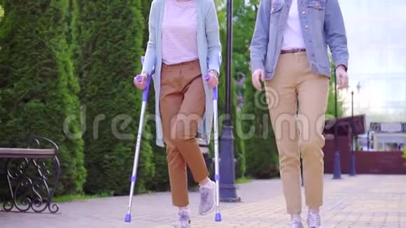 一位拄着拐杖受伤的年轻残疾妇女和一位朋友微笑着交谈视频的预览图