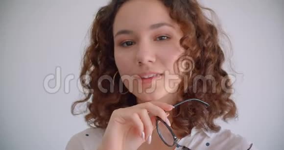 戴眼镜的白种人年轻漂亮长头发卷曲的女性特写照片笑着兴高采烈地看着镜头视频的预览图