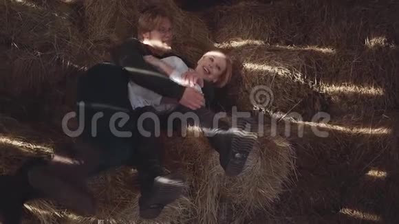 戴眼镜的长胡子帅哥和在寒冷的冬天谷仓里躺在干草上的漂亮女人快乐的一对牧场主视频的预览图