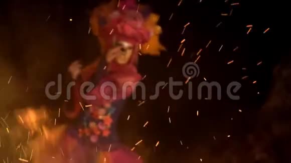 神秘的女孩穿着明亮的西装戴着金色的面具在炉火的照耀下跳舞视频的预览图