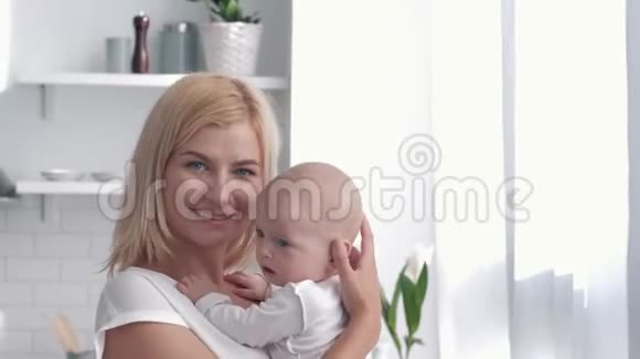 家庭幸福的肖像新妈妈在厨房拥抱亲吻新生女孩视频的预览图