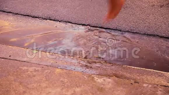 在金色的时刻一个赤脚的孩子站在水坑里轻轻的雨滴落下视频的预览图