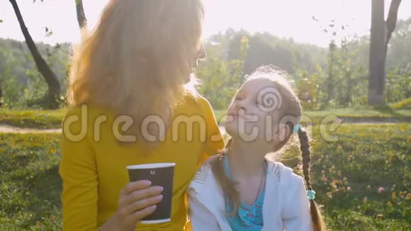 年轻的母亲穿着黄色衬衫一杯咖啡小可爱的女儿正享受着清晨的坐姿视频的预览图