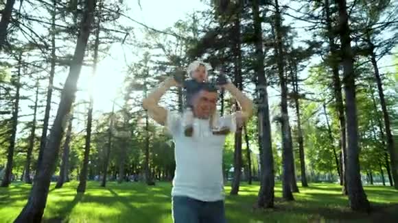 太阳照在父亲的肩上抱着他的小女孩在户外用镜头照明视频的预览图