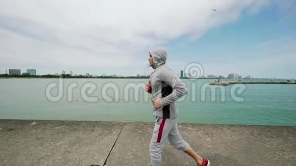 一个年轻的运动男子从事体育运动沿着湖边跑步慢动作视频的预览图