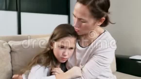 妈妈抚慰了女儿一个泪流满面的女孩坐在她母亲腿上妈妈和女儿抱着坐在沙发上视频的预览图