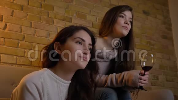 快乐的年轻白种人女孩坐在一起喝酒在舒适的家里交流的特写照片视频的预览图