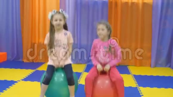 孩子们游戏室小女孩跳在体操球上视频的预览图
