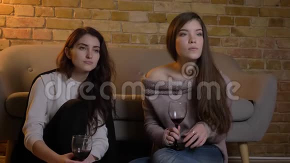年轻白种人女孩坐在地板上喝酒在舒适的家庭氛围中专心看电影的肖像视频的预览图