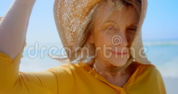 活跃的高加索族妇女戴着帽子站在海滩上的正面景色视频的预览图