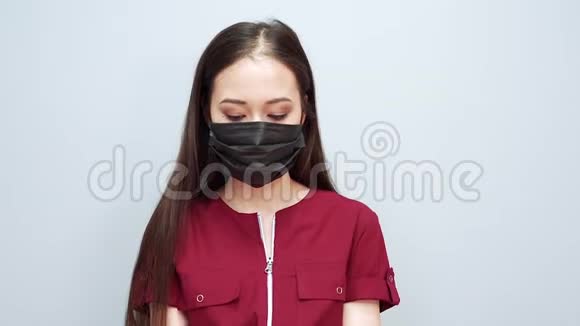 戴黑色手套戴灰色背景防护面具的严肃女人视频的预览图