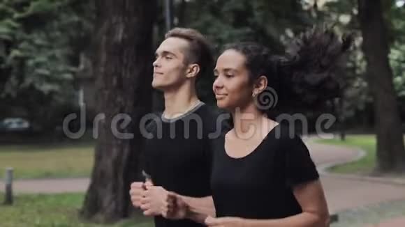 年轻的白种人夫妇穿着慢跑套装微笑着聊天在公园里跑步健康视频的预览图