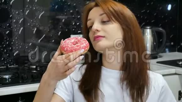 饥饿的年轻长发女孩在家里的厨房里吃红面圈美味的食物概念视频的预览图