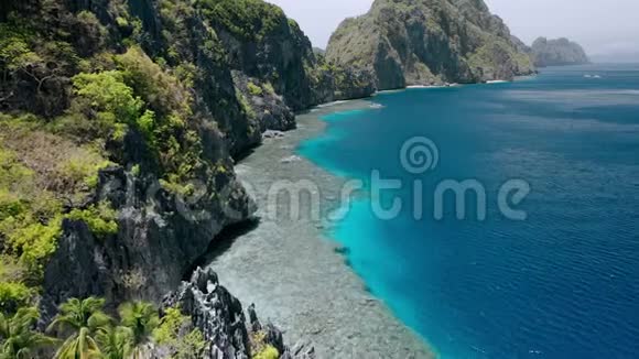 在旅游船落基山脉和马丁洛克神殿附近的珊瑚礁上空的空中飞行画面菲律宾巴拉望ElNido视频的预览图