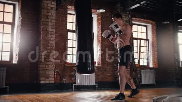 一个体育健将在明亮的体育馆训练他的拳击技能视频的预览图