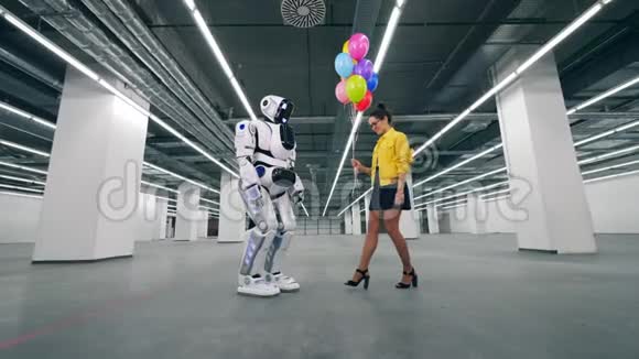 年轻女子把气球送给一个高大的机器人视频的预览图