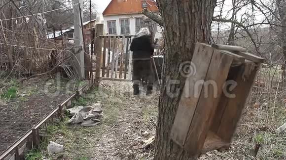 可怜的老奶奶穿过这片土地走到摇摇欲坠的大门和倒塌的老房子视频的预览图