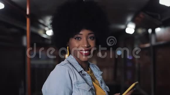 非裔美国妇女看着相机微笑着站在公共交通工具stealicam拍摄她抱着她视频的预览图