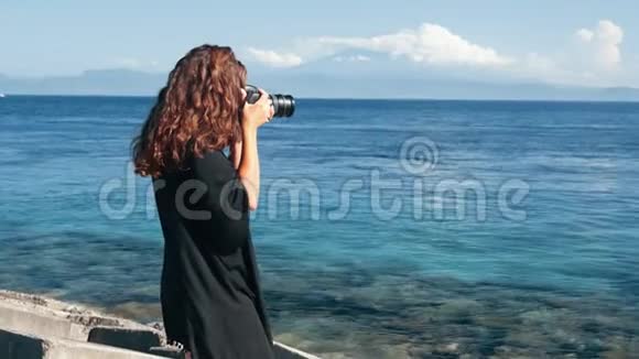 女孩摄影师的侧视拍摄海洋和山脉的照片视频的预览图