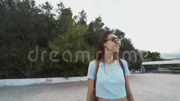 外面的画像是一个年轻漂亮开朗微笑的女士穿着休闲装小背包站在海边视频的预览图