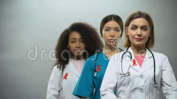 戴着红色丝带和双手交叉的严肃女护士对艾滋病的认识视频的预览图