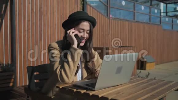 女士用手机聊天在露天咖啡馆里用笔记本电脑打字视频的预览图