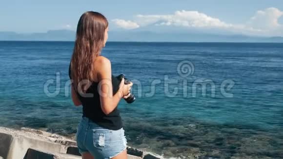 女游客摄影师的侧景拍摄海洋和山脉的照片视频的预览图