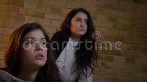 两个年轻的白种人女孩坐在客厅里以极大的乐趣看电视视频的预览图
