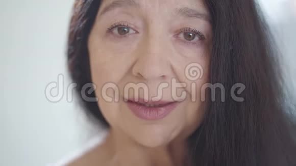 一幅美丽的悲伤的不快乐的老年妇女的肖像一头乌黑的长发在镜头中哭泣眼睛里充满了泪水视频的预览图