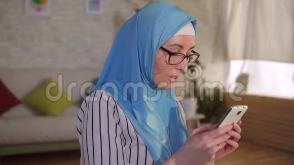 戴着头巾脸上有一道伤疤的年轻穆斯林妇女使用智能手机视频的预览图