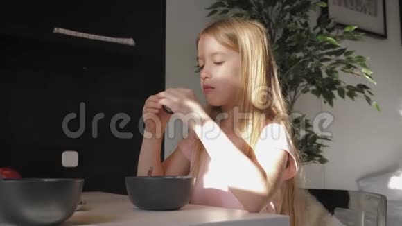 可爱的十几岁的女孩坐在餐桌前早餐吃粥健康的生活方式观念视频的预览图