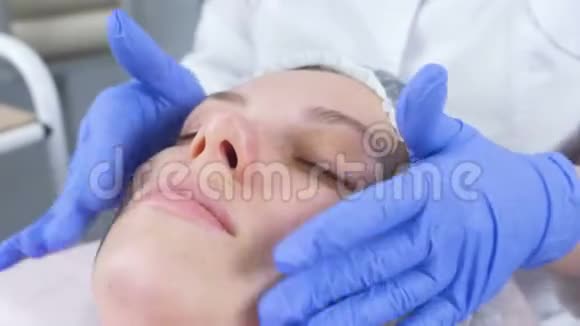 美容师把奶油放在女人脸上美容师面部治疗特写镜头视频的预览图
