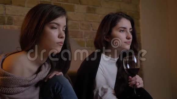 特写镜头描绘了年轻的白种人女孩专心看电视在舒适的家喝葡萄酒视频的预览图