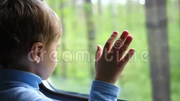 这个男孩坐火车旅行望着窗外看着窗外移动的物体手工特写视频的预览图