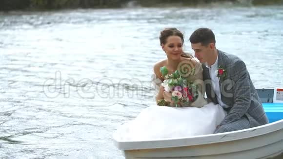 新婚夫妇在小船上缓慢地漂浮着人们开心地笑着视频的预览图